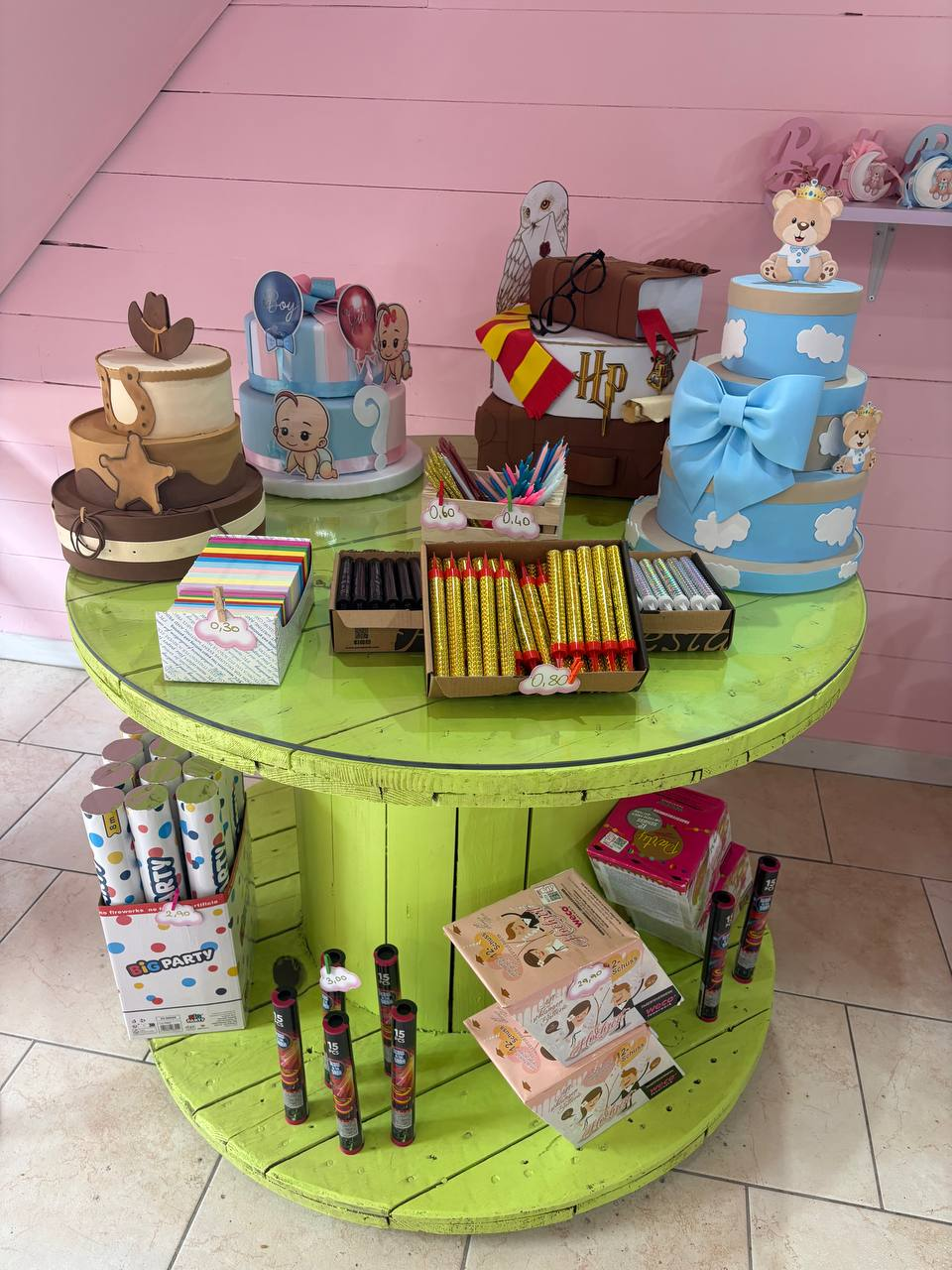 Tavolo espositivo con torte scenografiche a tema cowboy, baby boy, Harry Potter e celeste con fiocco, candeline e tubi di coriandoli